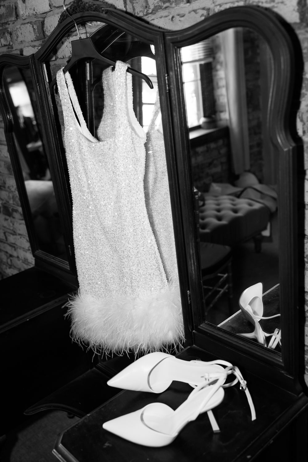 White wedding dress and shoes displayed in front of an elegant mirror.