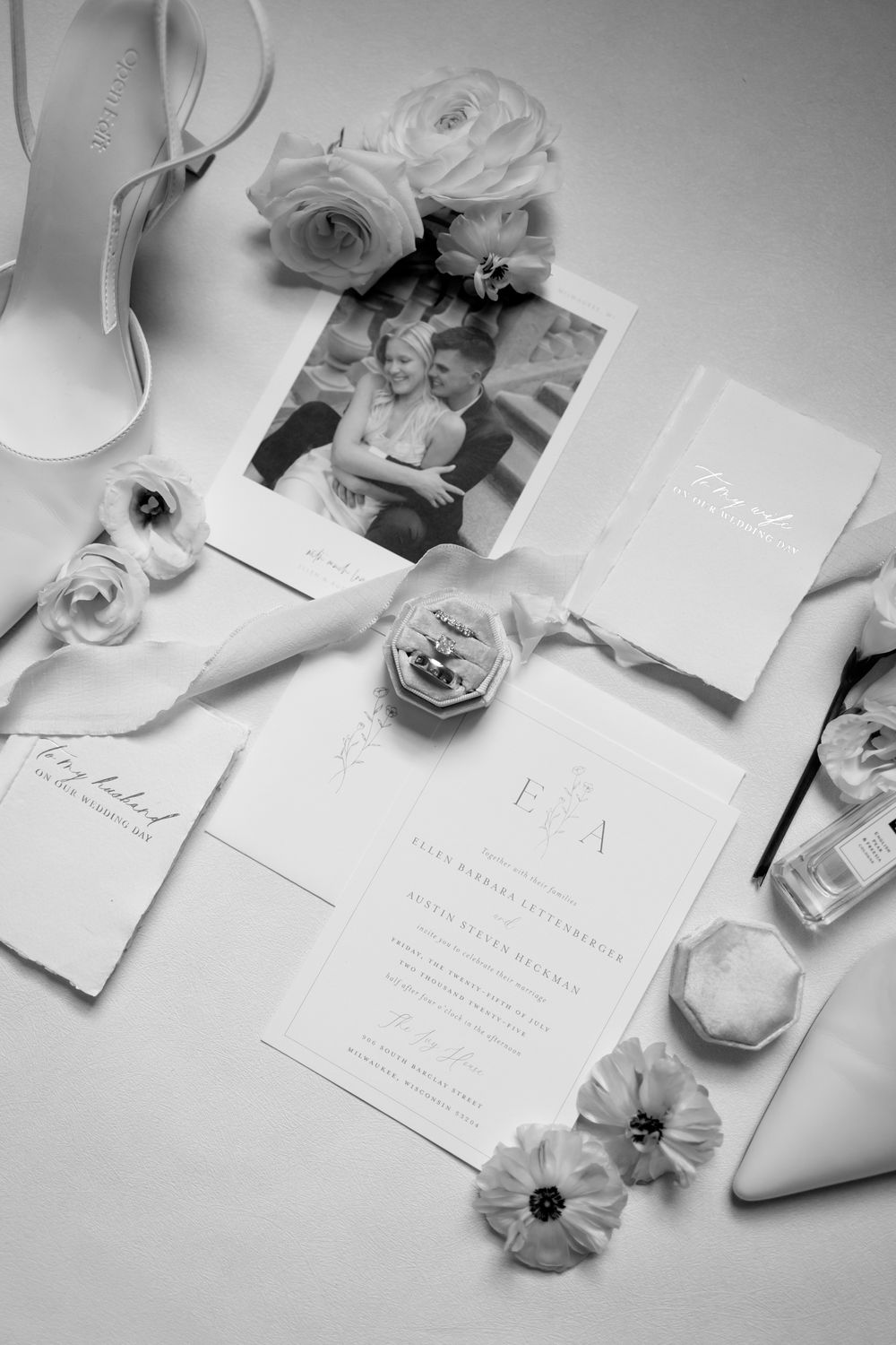 Elegant wedding stationery and floral details arranged in black and white with delicate roses and invitation cards.