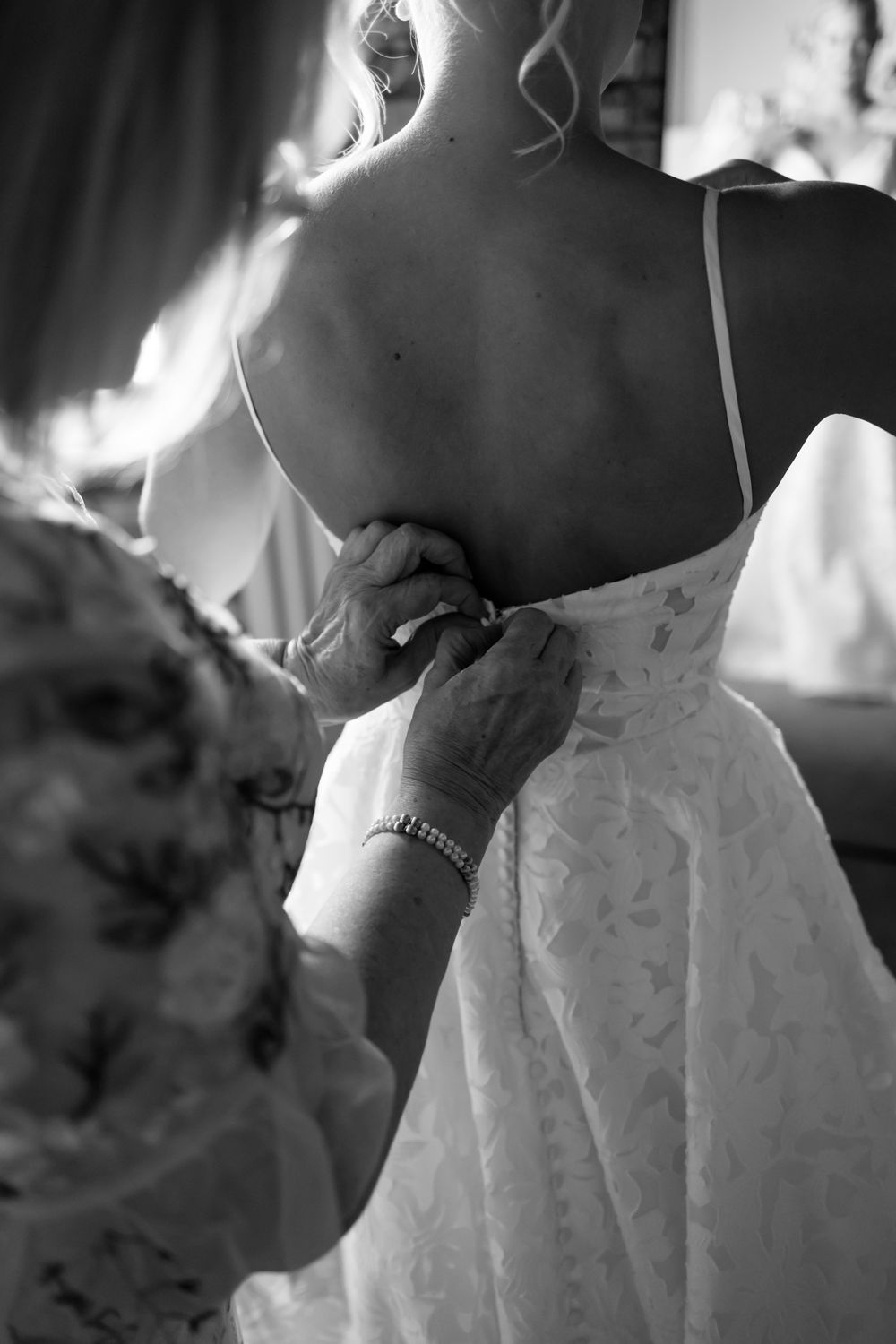 Black and white photo showing final adjustments being made to a wedding dress.