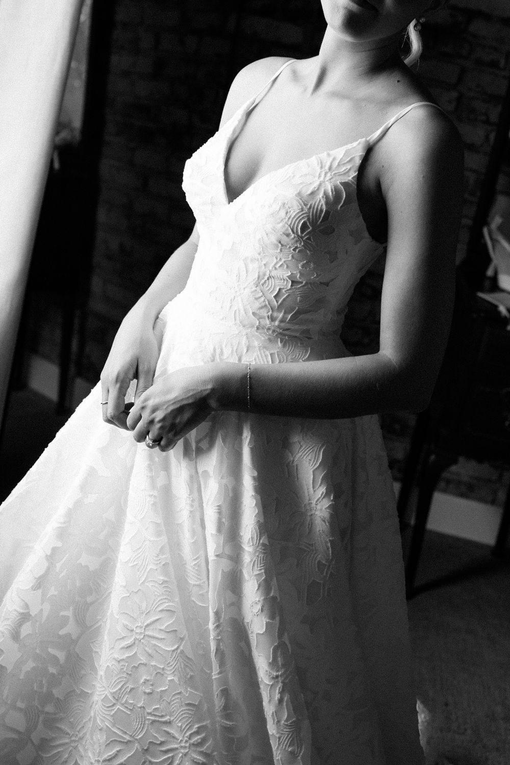 Close-up details of a white lace wedding dress with delicate floral embroidery patterns.