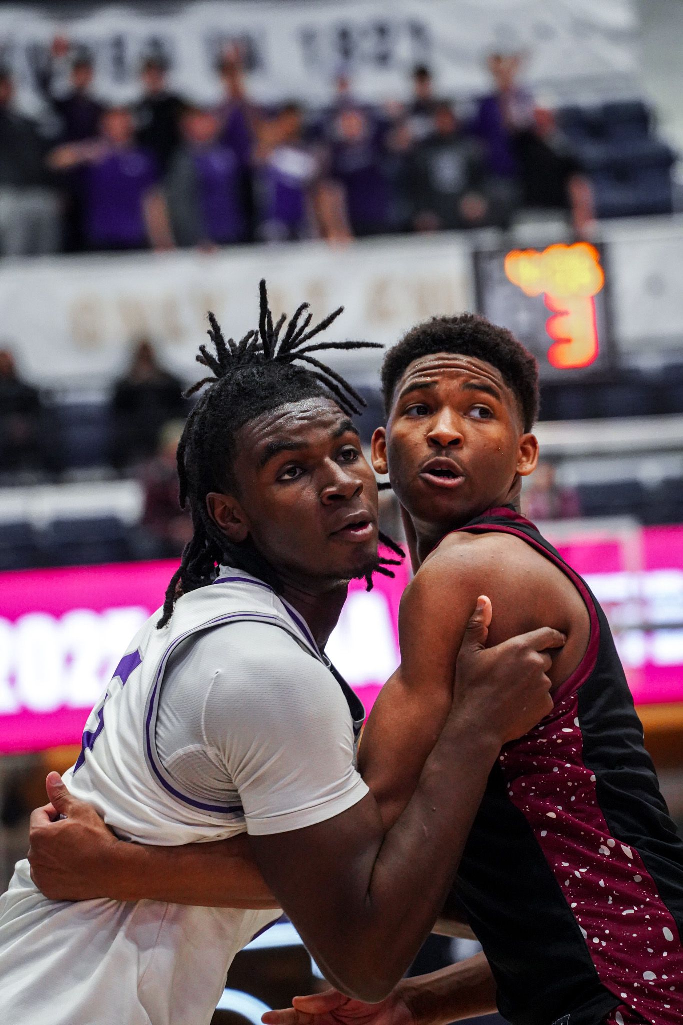 Two basketball players compete for a rebound during an intense game action sequence.