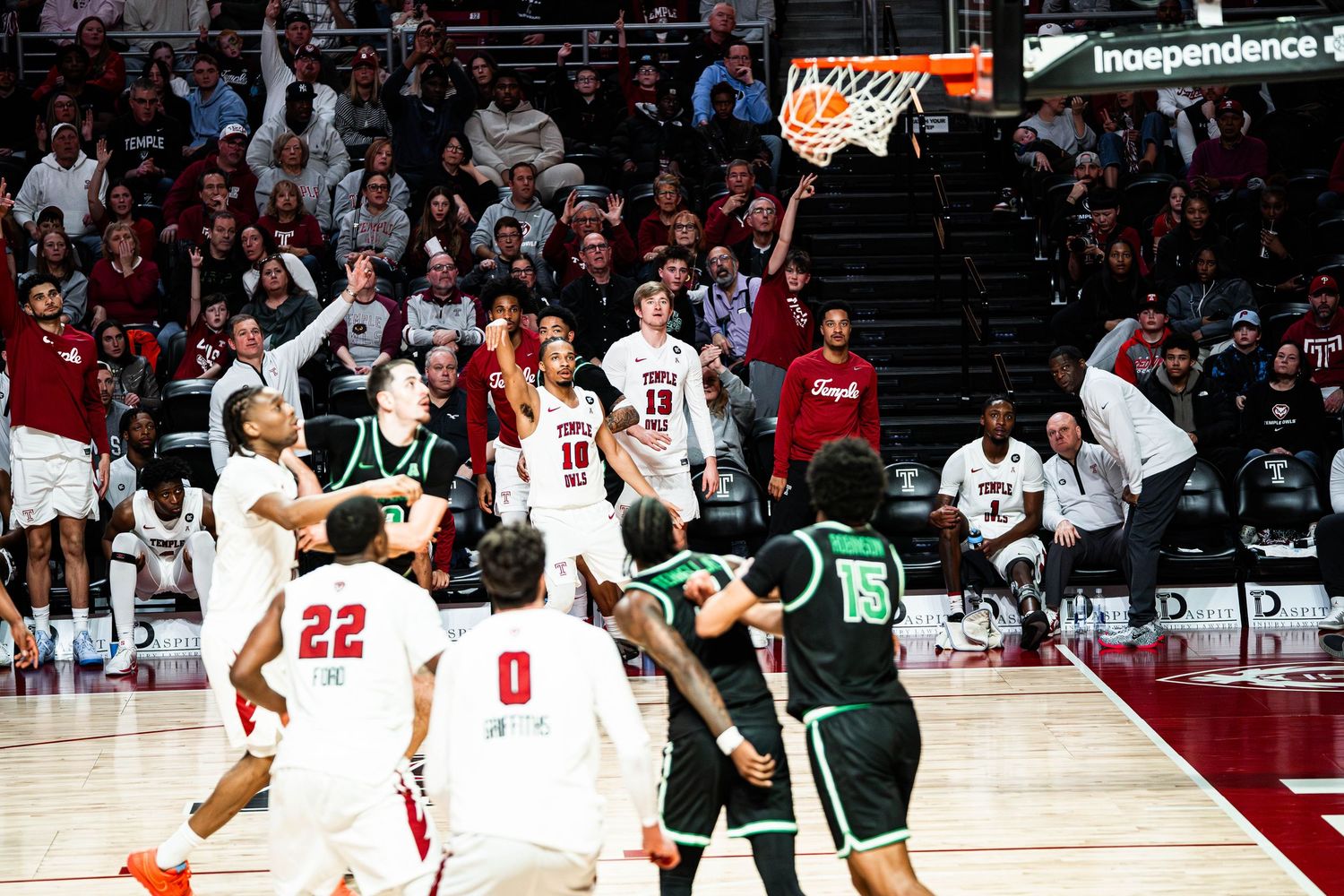 Basketball players compete during an intense college game with fans cheering in the background.