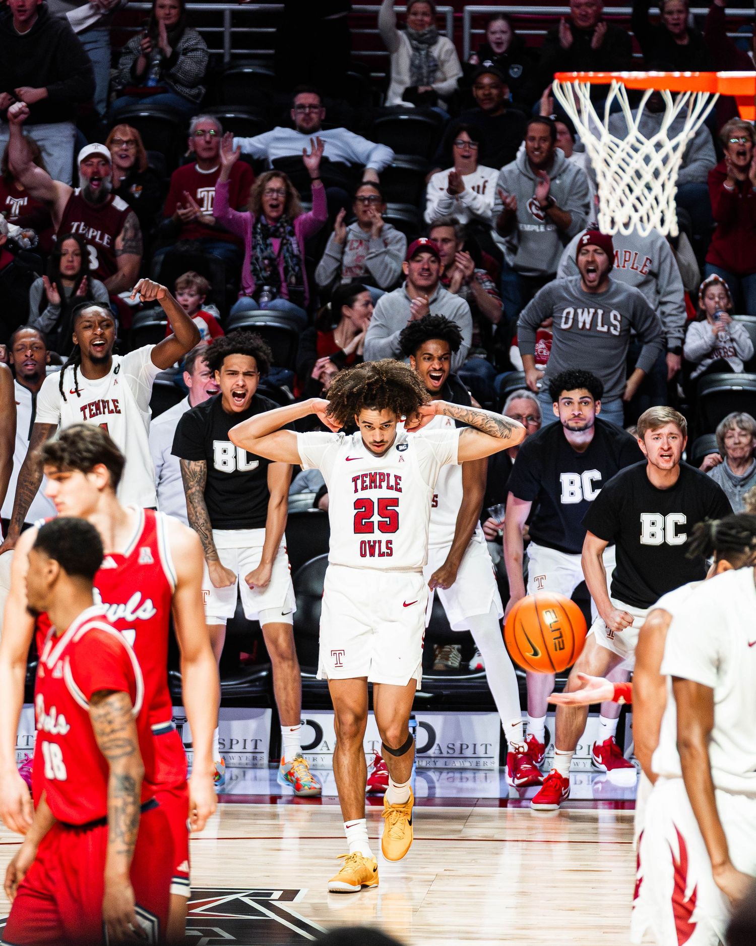 Basketball players celebrate on the court during an intense game between Temple and Boston College.