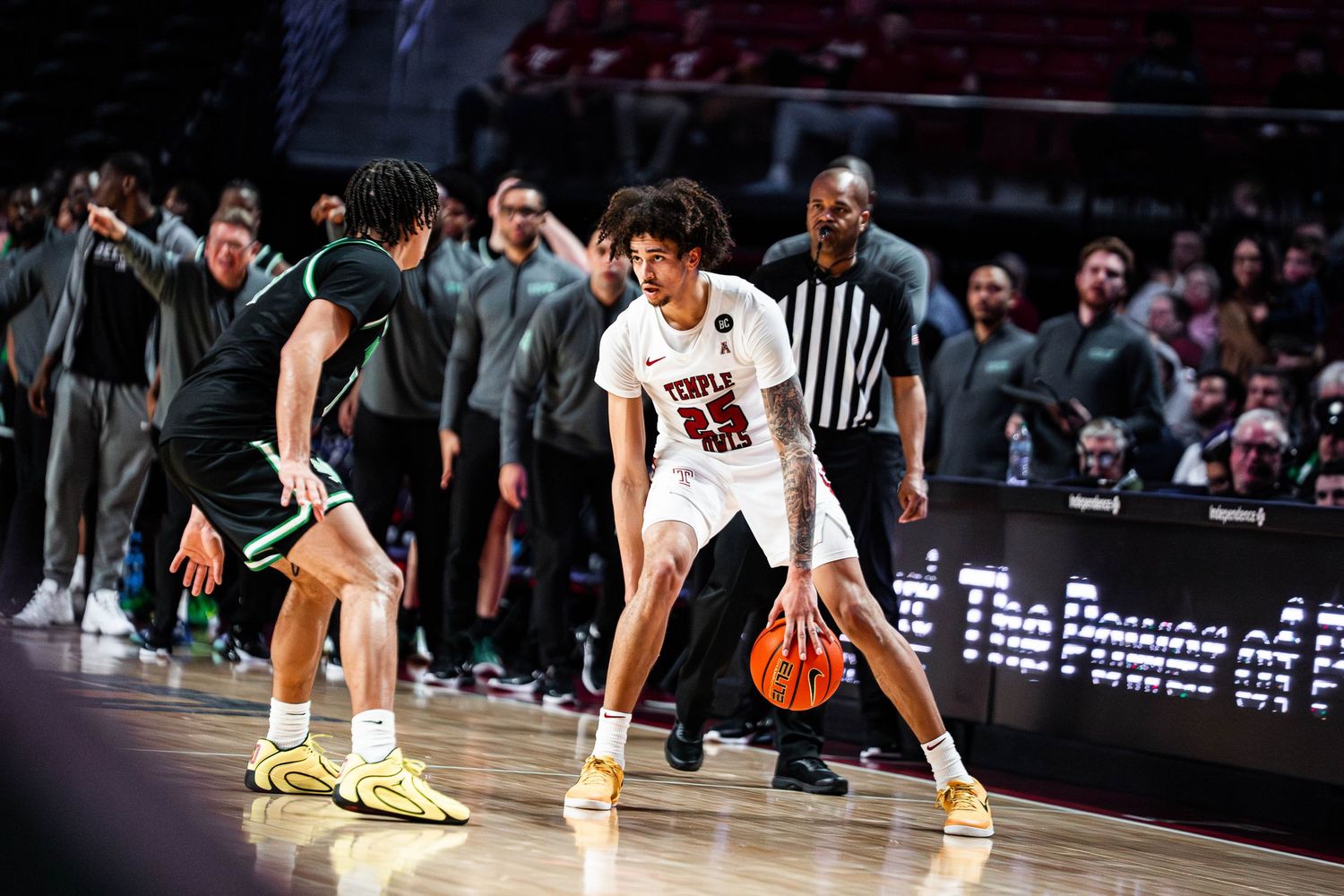 A basketball player dribbles the ball during a game while being defended on the court.
