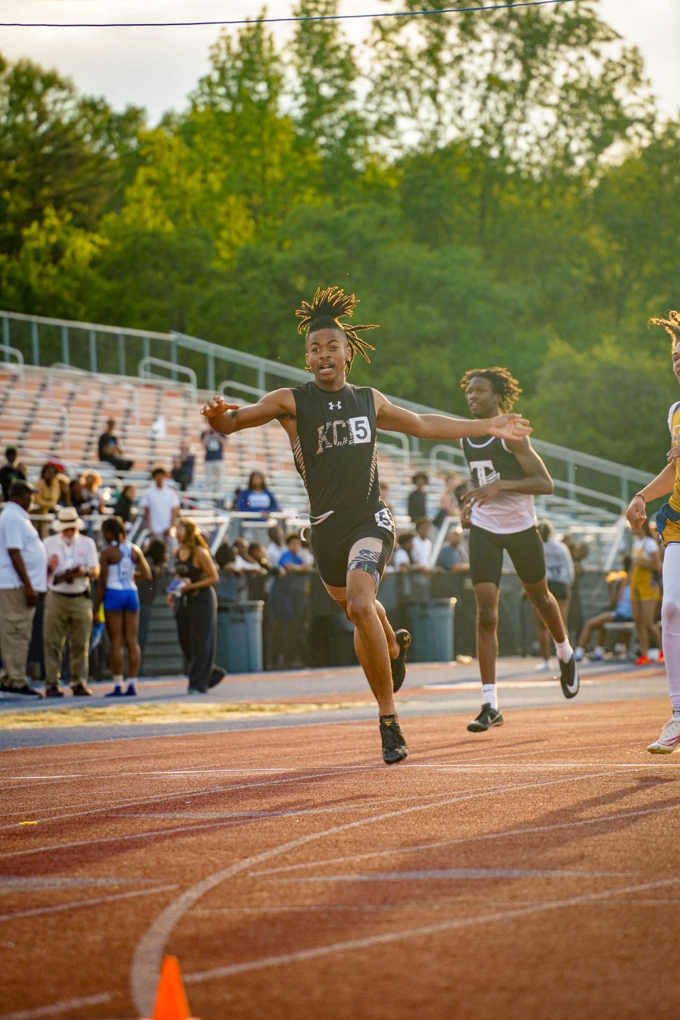 A sequence of action shots showing a track athlete performing a long jump at an outdoor stadium during competition.