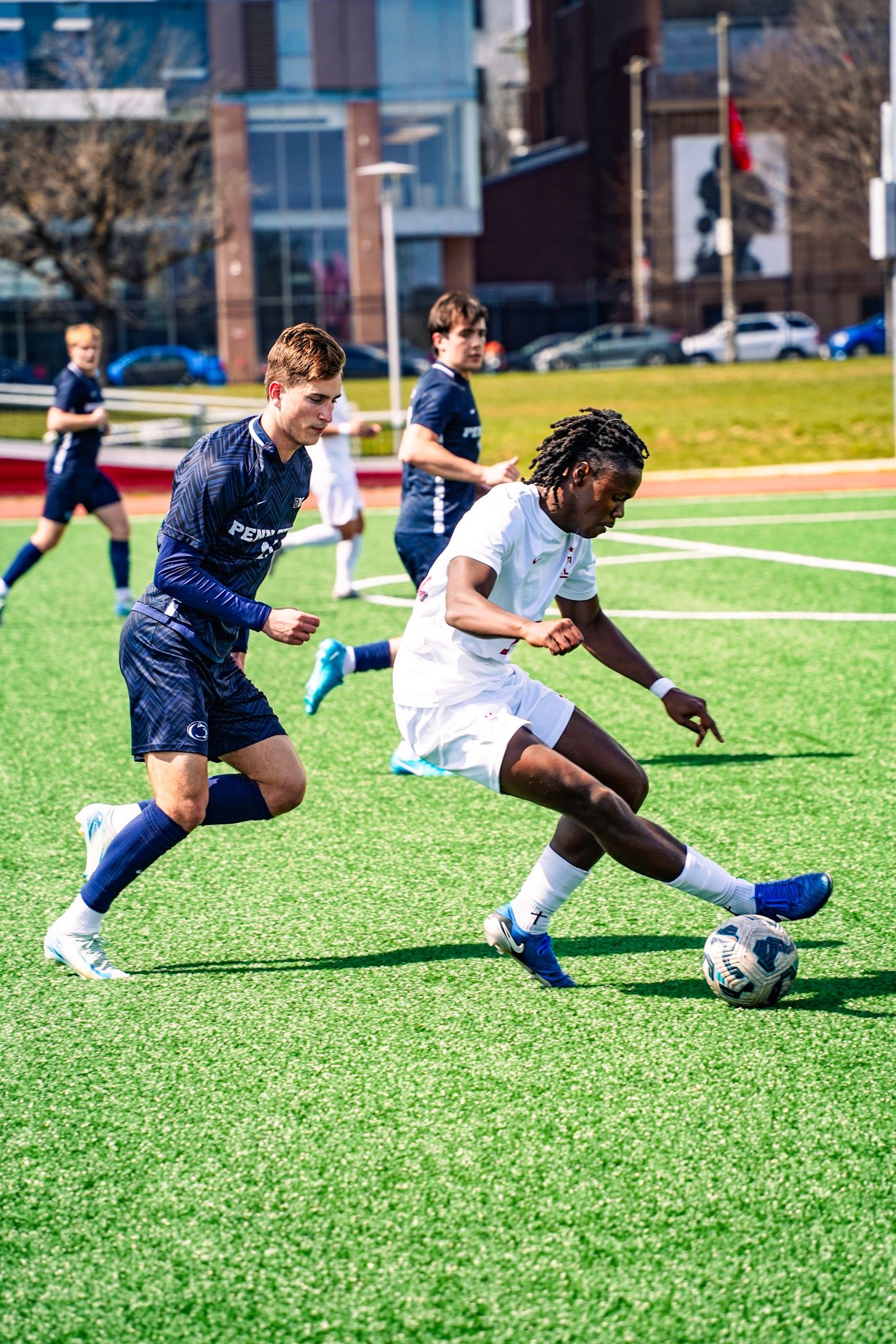 Soccer players compete for possession of the ball on an artificial turf field during an intense match.