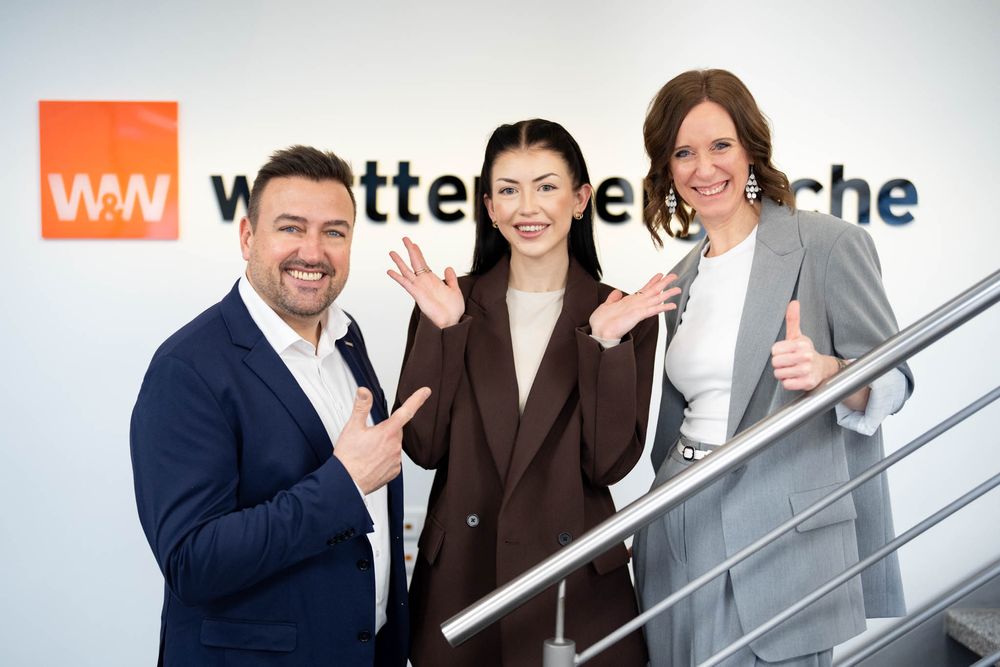 Business professionals in suits gather on modern office staircase for group photo.