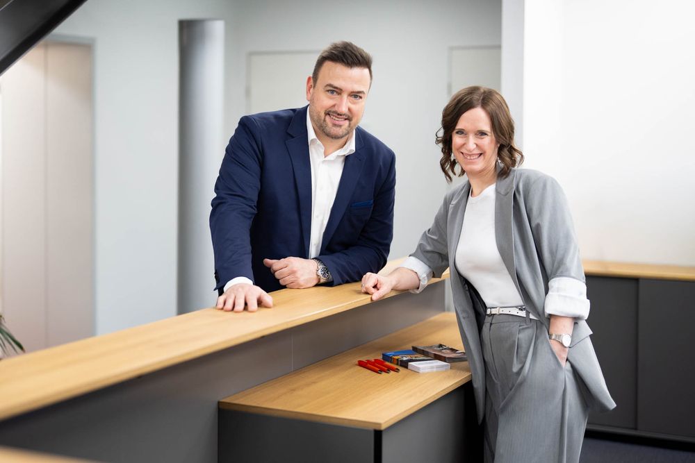 Business professionals in formal attire collaborate at a wooden conference table in a modern office setting.