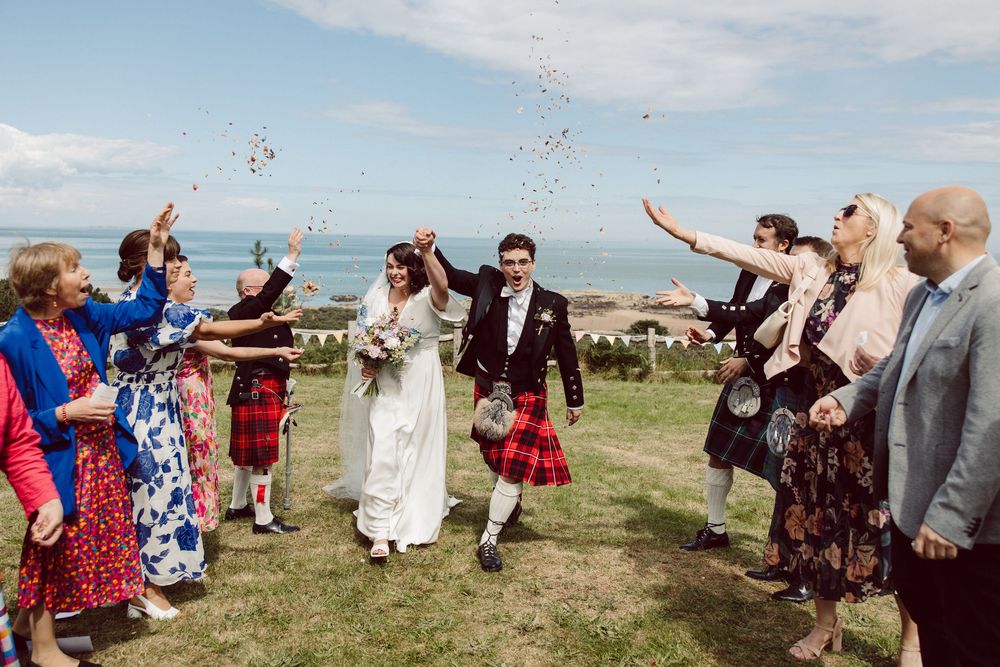 A panoramic sequence of wedding guests celebrating outdoors in a grassy field on a sunny day.