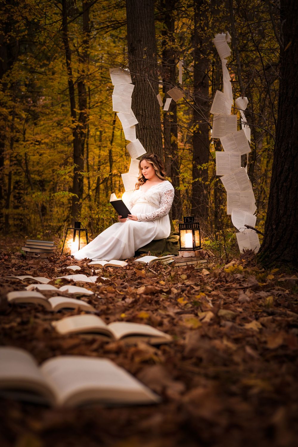 A person in a white dress reads a book in an autumn forest setting illuminated by warm lantern light.