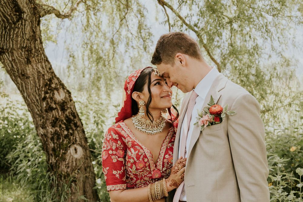 Intimate wedding moment under a willow tree with traditional red bridal attire.