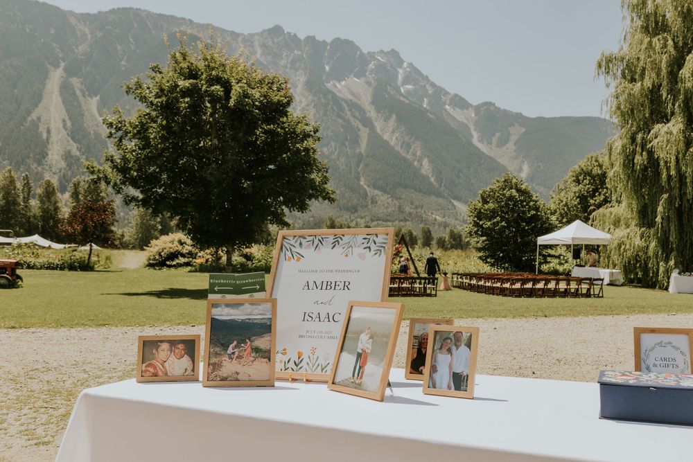 Wedding photos and signage displayed on a table with scenic mountain landscape backdrop.