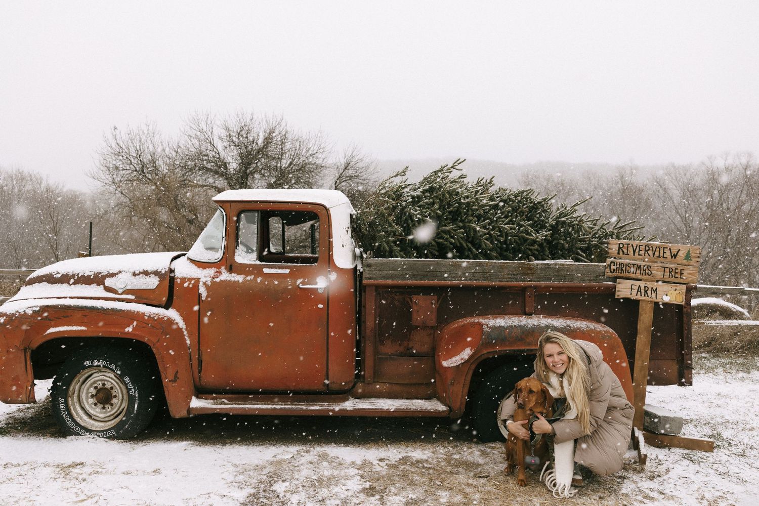 A vintage rusty orange pickup truck sits abandoned in a snowy winter landscape.
