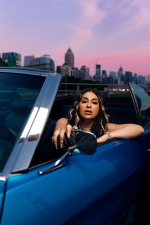 A series of moody photos show a person in a blue car at sunset against a city skyline backdrop.