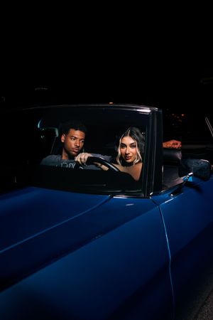 Nighttime photo of people inside a vintage blue car.
