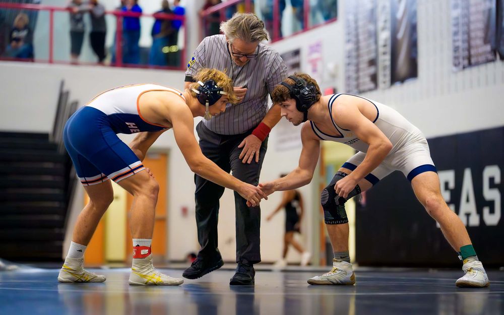 Christian Burd in blue singlet acknolages his opponent on the mat during the milestone 100th win wrestling match.