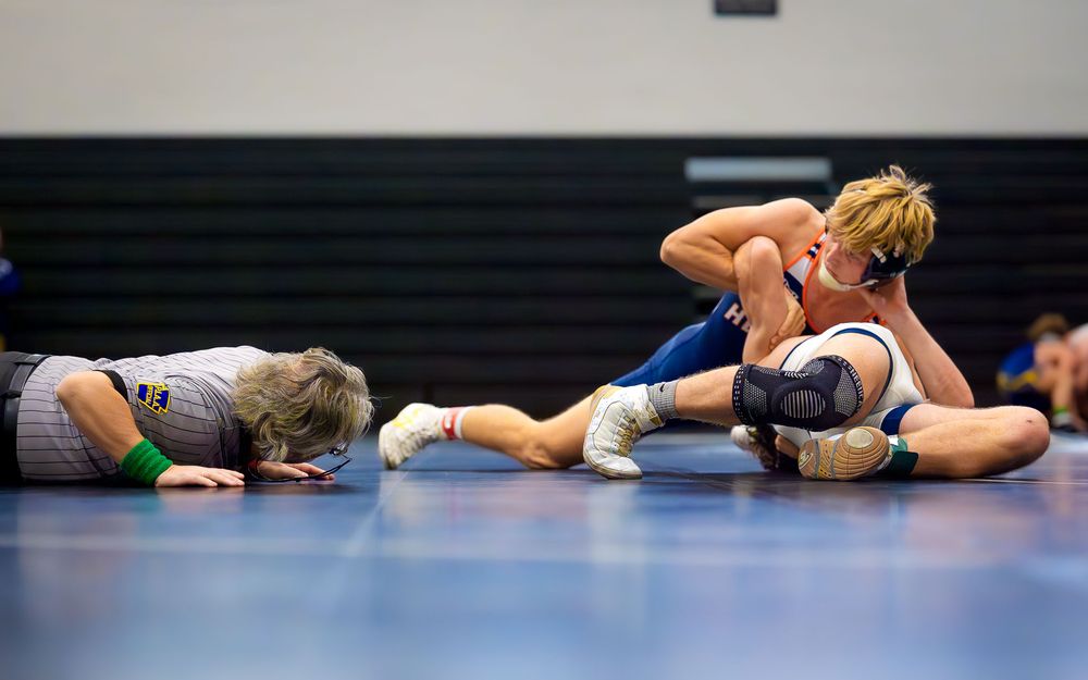 Christian Burd in blue Hershey singlet wrestling opponent on the mat during his milestone match.