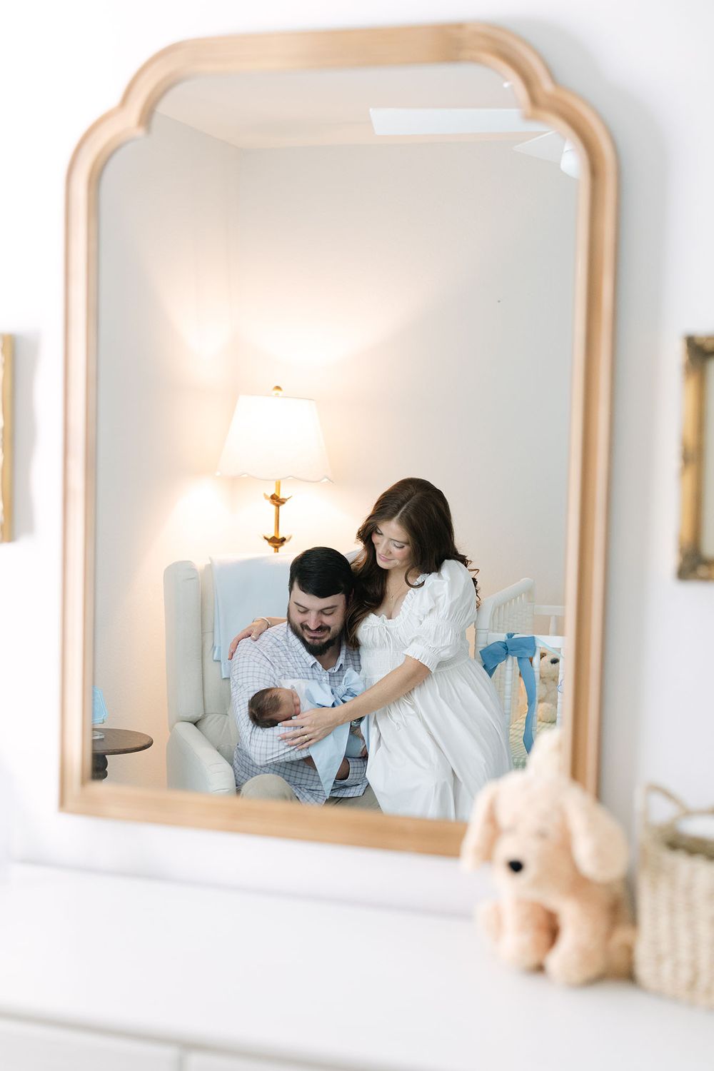 Mom and dad holding newborn baby boy in his nursery. Image captured through the reflection of the mirror by Mobile, AL Newborn Photographer.