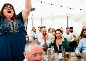 Joyful wedding guests celebrating and laughing together at a marquee reception.
