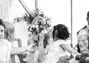 Black and white photo of emotional bride in flower crown crying during wedding ceremony.