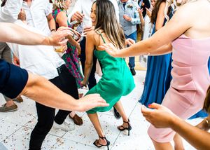 Woman in green dress dancing energetically at a lively wedding reception party.