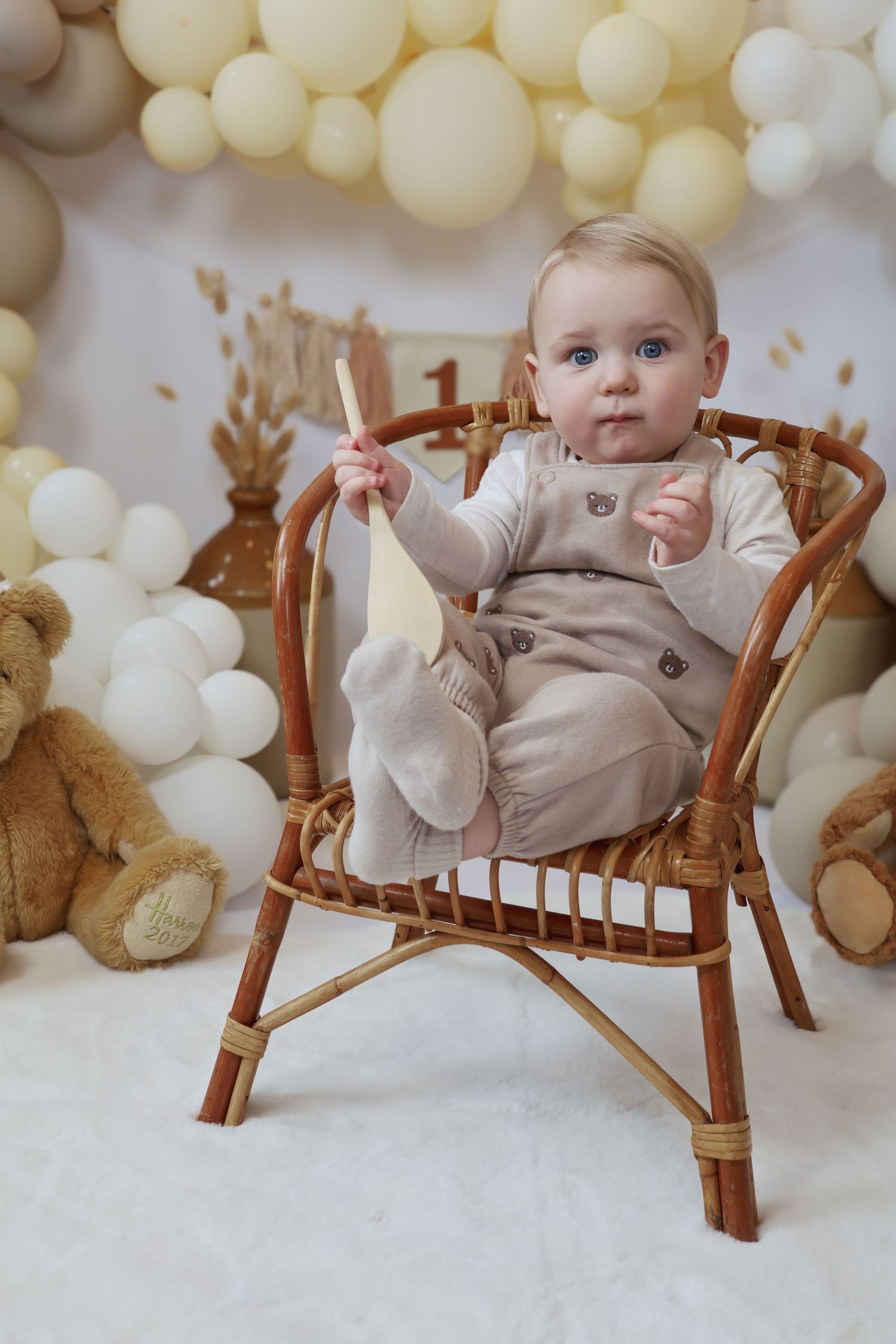A small child in a plaid dress sits on a white rocking horse near decorated Christmas trees with white bows.