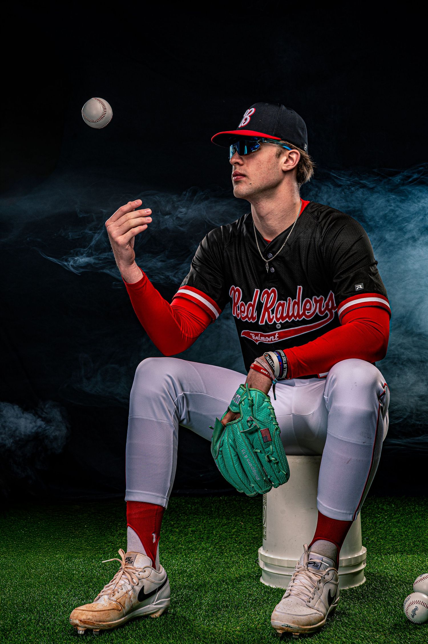 Baseball player in red uniform crouching on bucket with dramatic smoke effects.