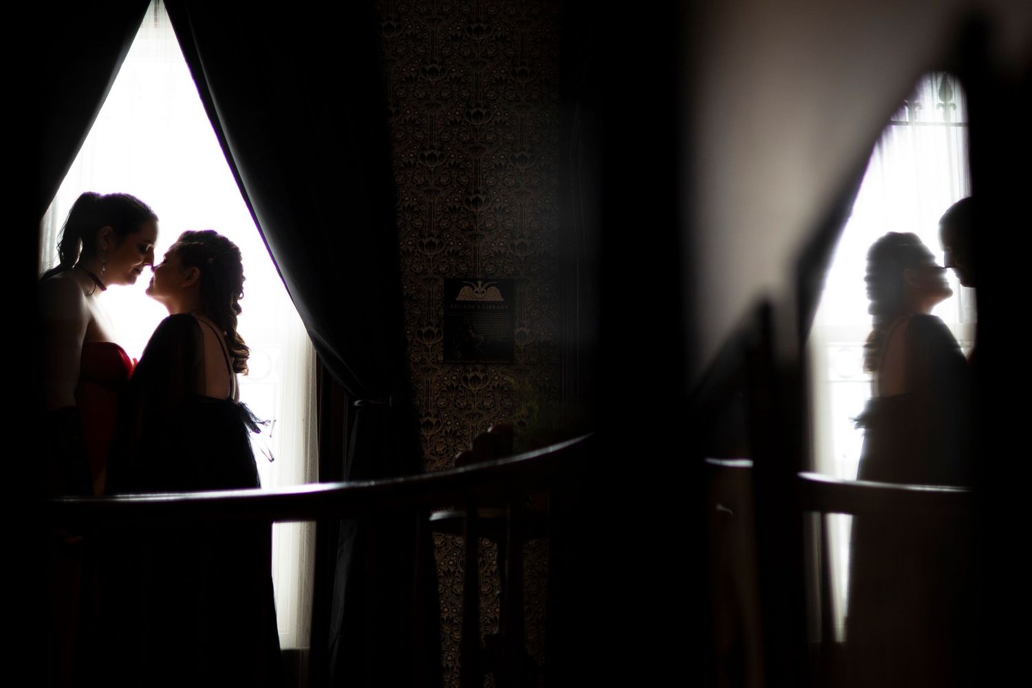 A series of dark silhouettes against bright windows create a dramatic contrast in black and white wedding photography.