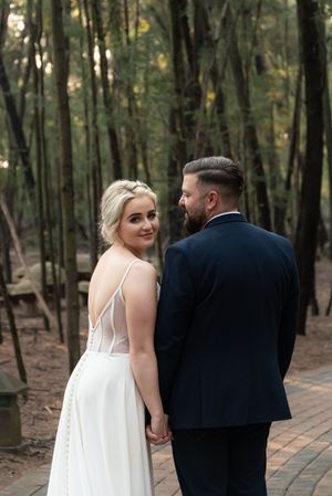 Bride and groom walking hand in hand during wedding portraits in forest in Gauteng