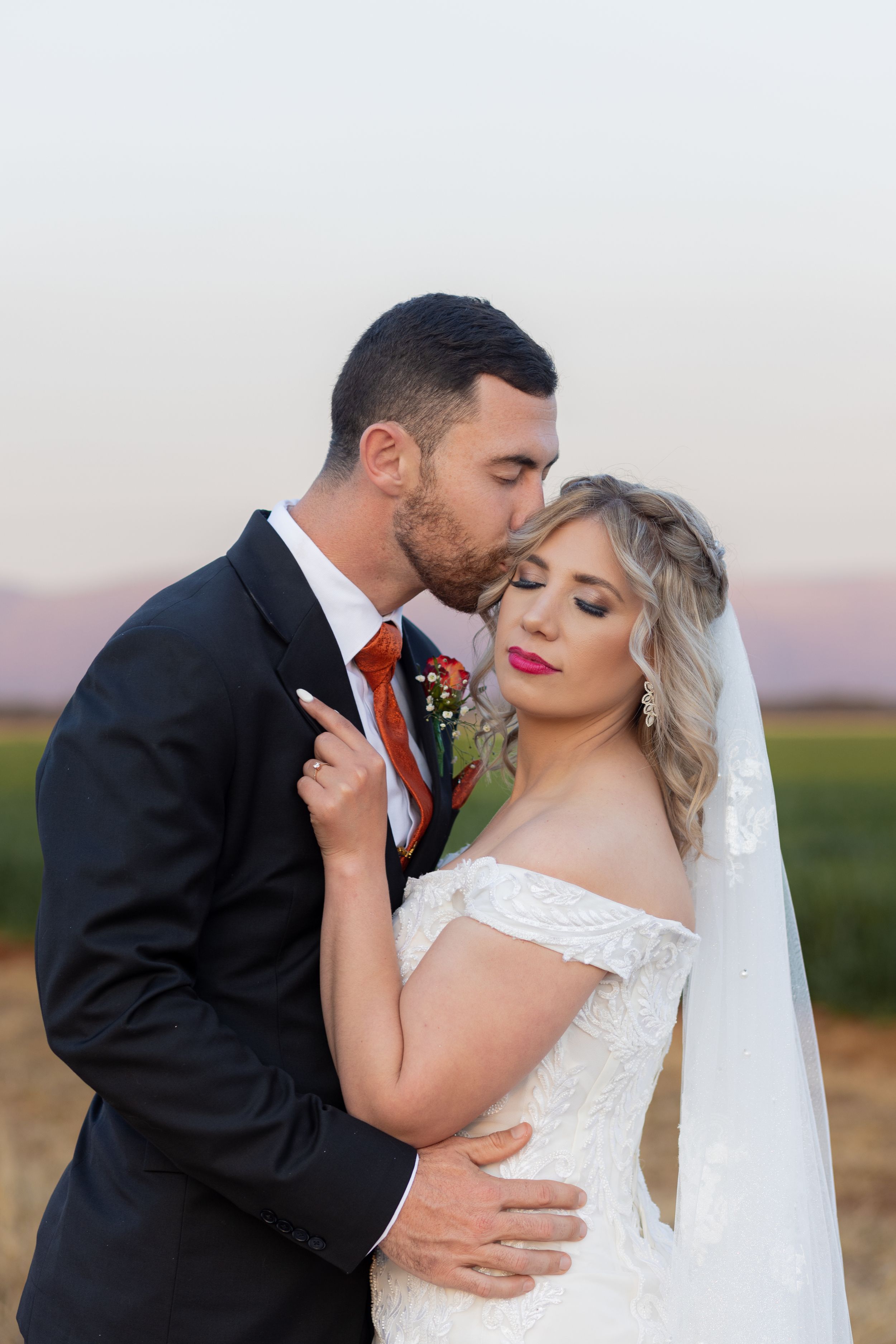 Groom kissing bride on forehead during wedding portraits in Gauteng with natural, romantic style