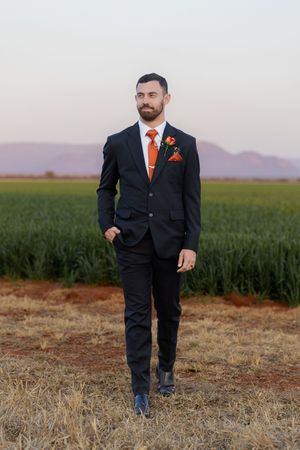 Groom walking through field during wedding portraits in Gauteng