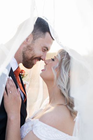 Bride and groom smiling under veil during wedding portraits in Gauteng with soft, natural light