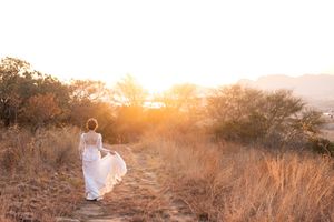 Bride walking through field at sunset during wedding in Gauteng