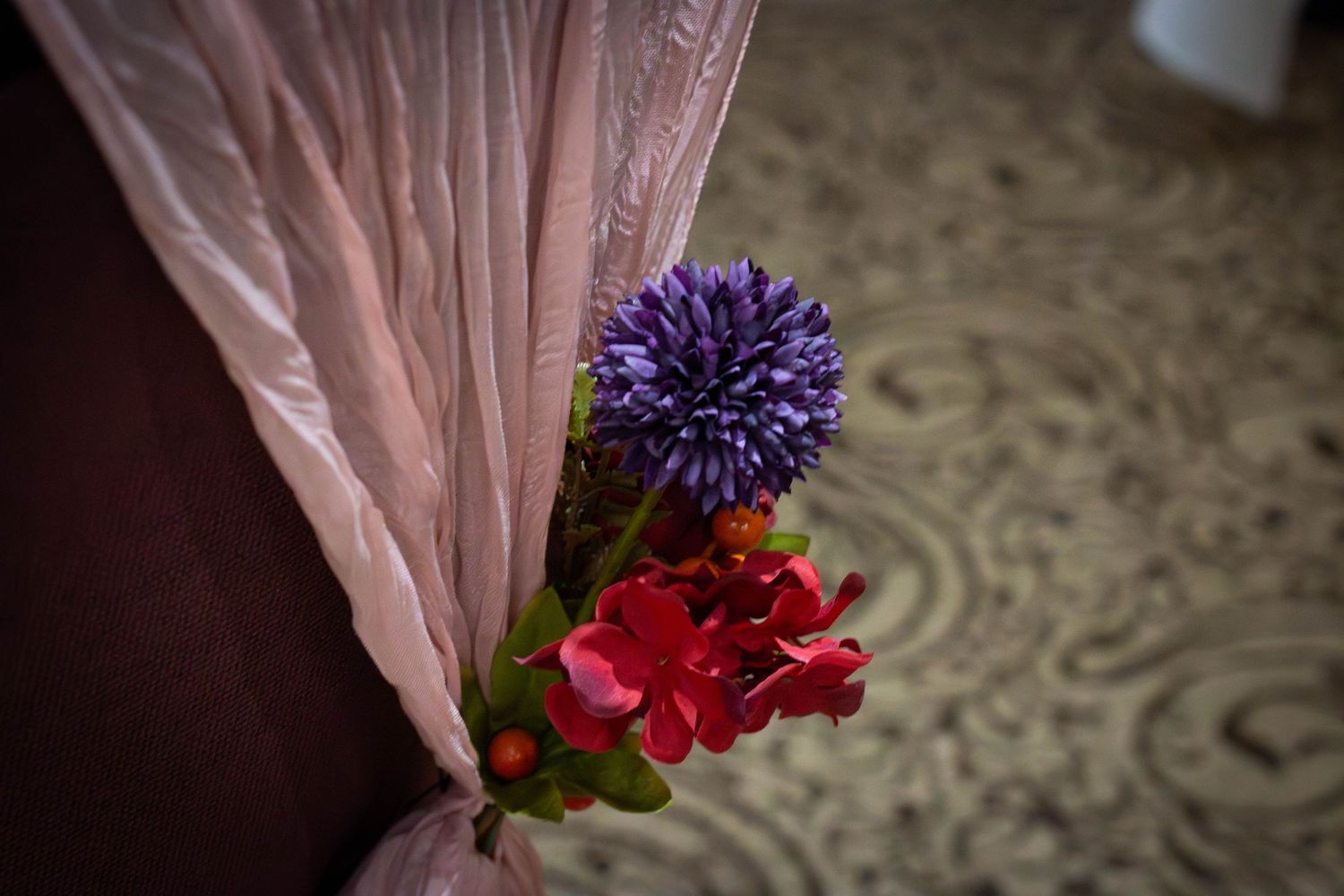 A row of colorful floral boutonnieres with pink and purple blooms arranged against a light pink background.
