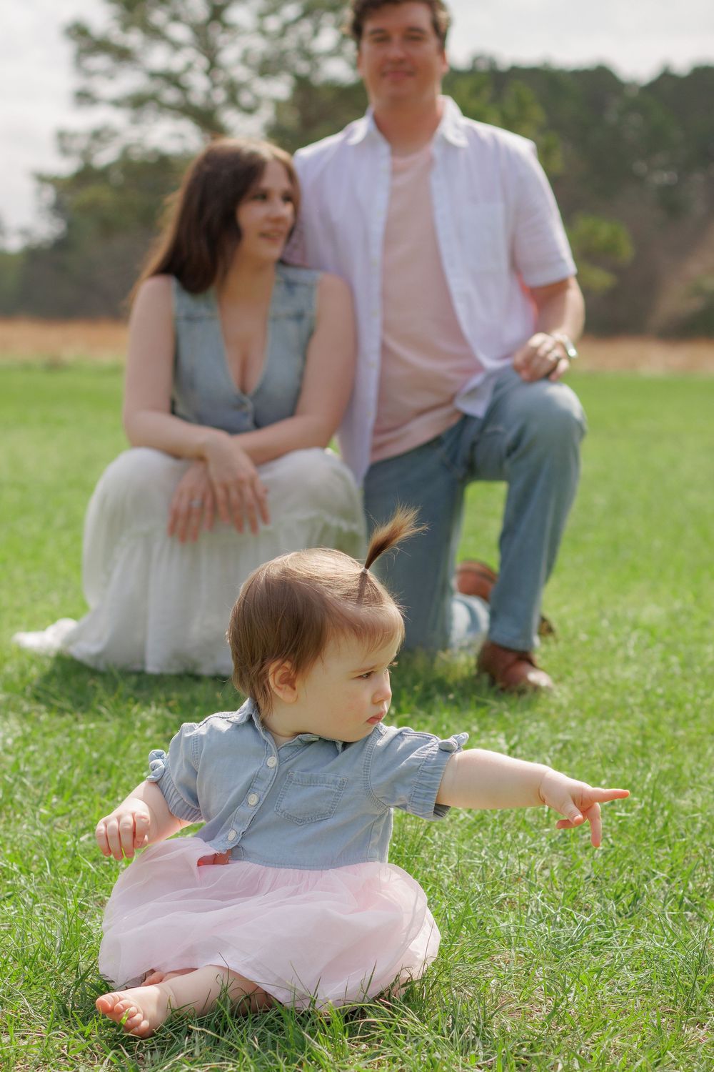 A young family enjoying a peaceful moment in a grassy field.
