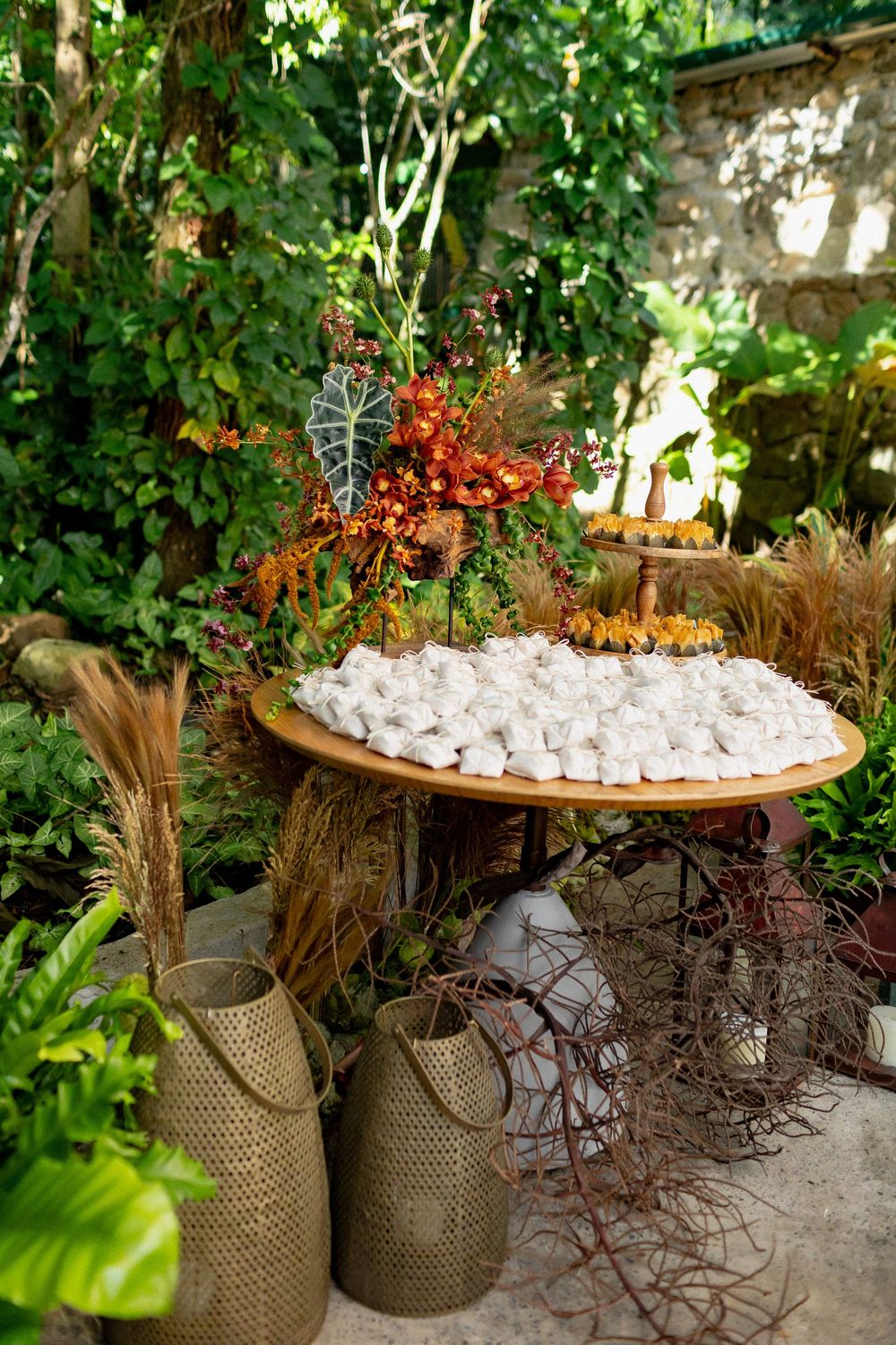 White meringues displayed on wooden table with dried flowers and woven baskets in a garden setting.