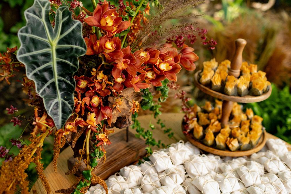 Colorful autumn floral arrangement with orange flowers, yellow berries, and white cotton stems on rustic wooden surface.