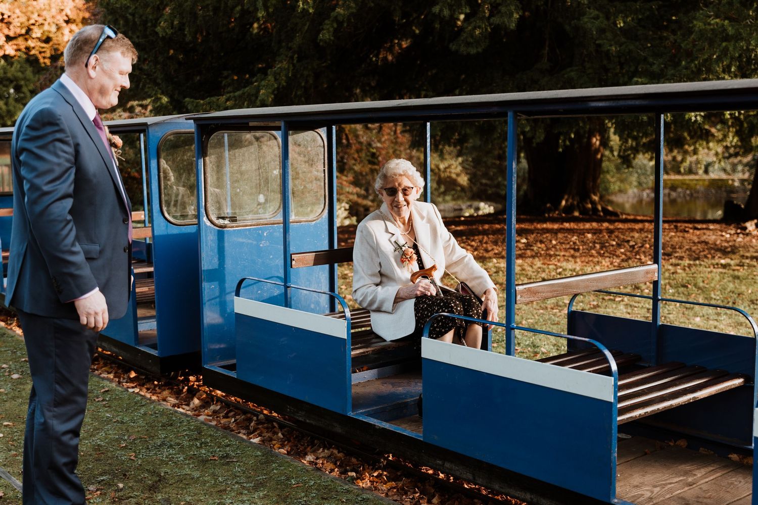 Nan on bright blue miniature train car surrounded by autumn leaves.