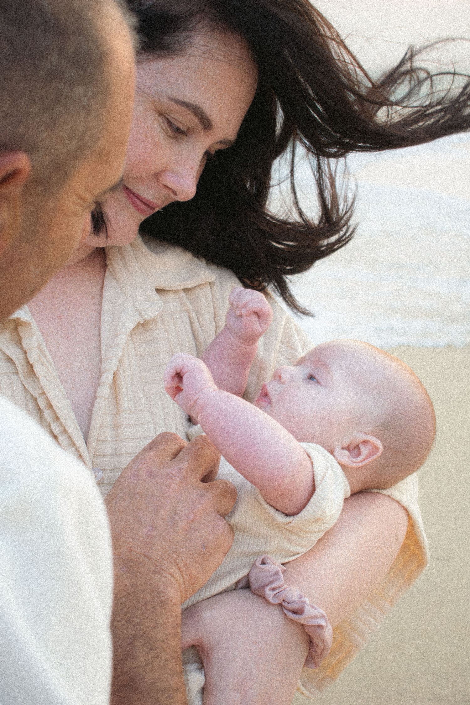 Newcastle newborn baby photographer capturing a sleepy baby in natural golden hour light with new mother and father