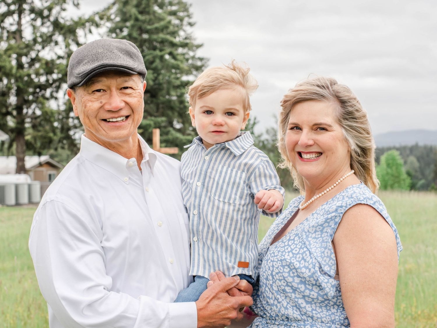 Family members share joyful moments together in an outdoor field setting during a casual photo session.
