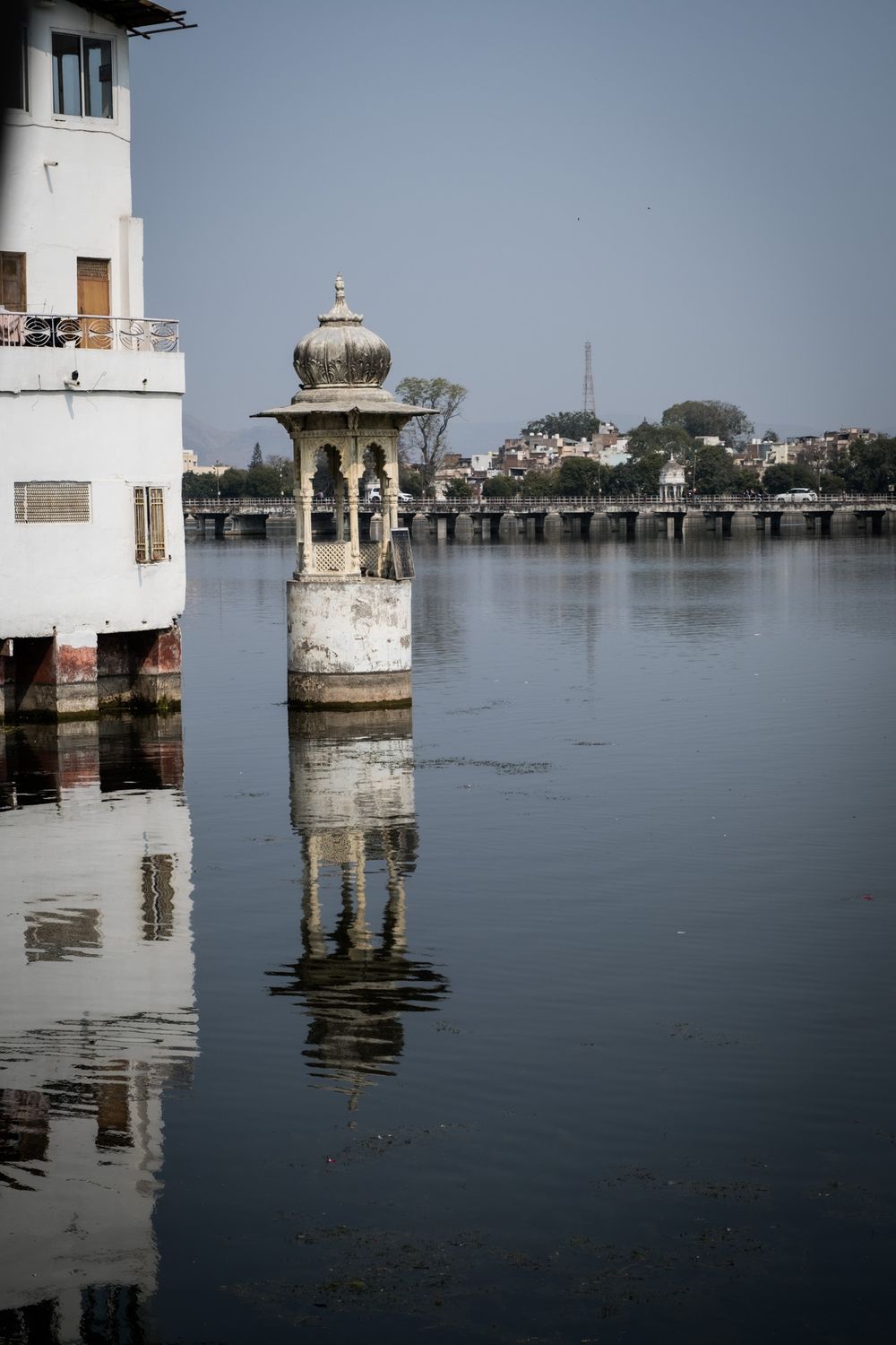 Historic white marble pavilion standing in lake waters with perfect reflection, Udaipur, Rajasthan, India.