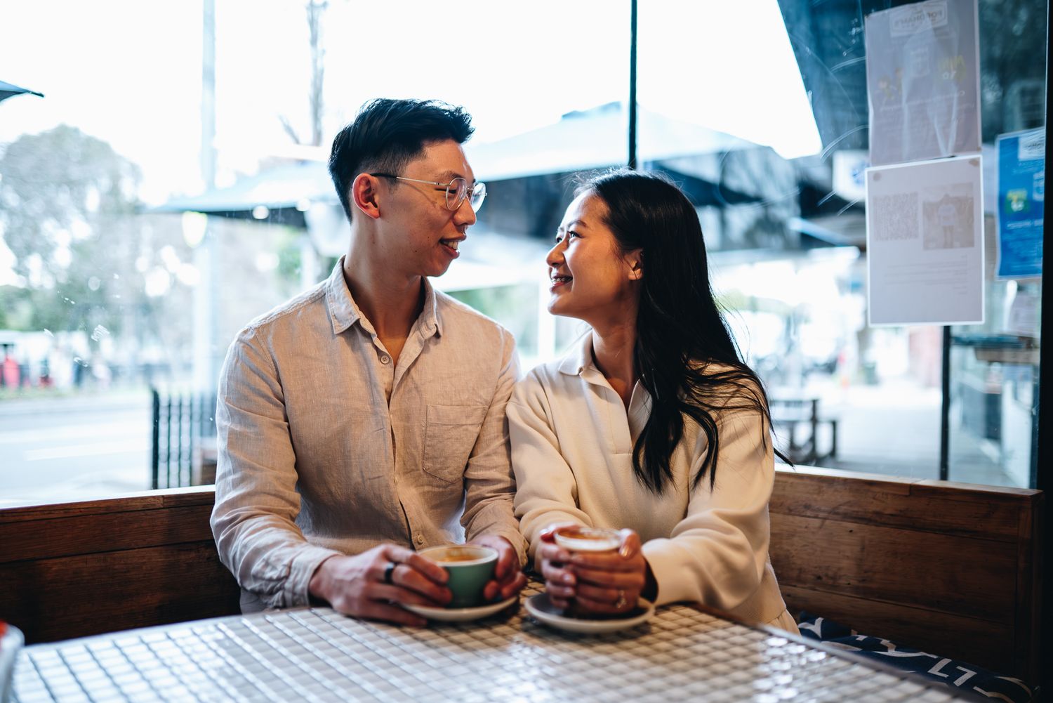 Two people share a joyful moment while dining together at a cafe taken during a casual couples photo session in Melbourne.