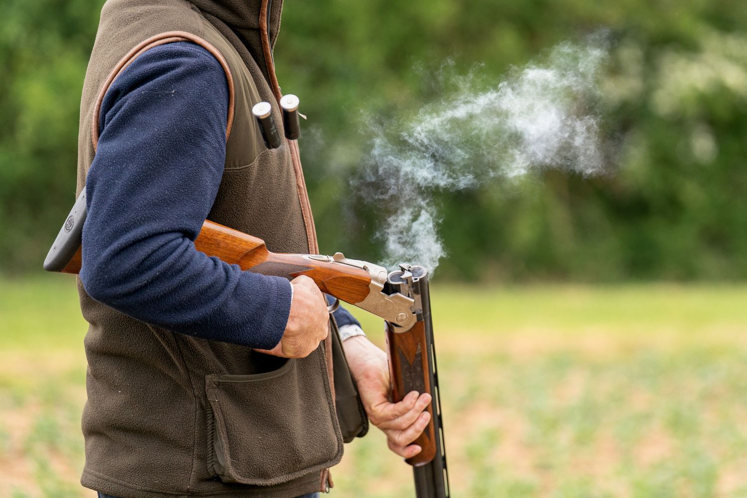 Two hunters in country attire walk a pack of gun dogs along a woodland path.