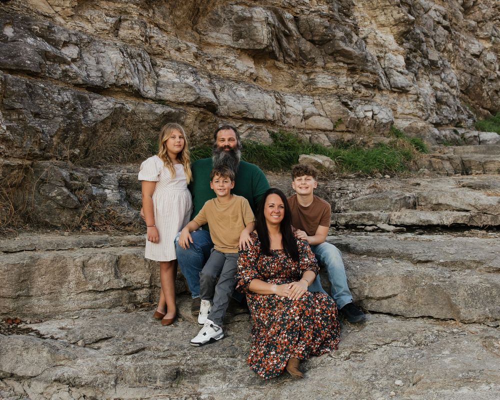 A family portrait taken against a dramatic rocky cliff face backdrop.