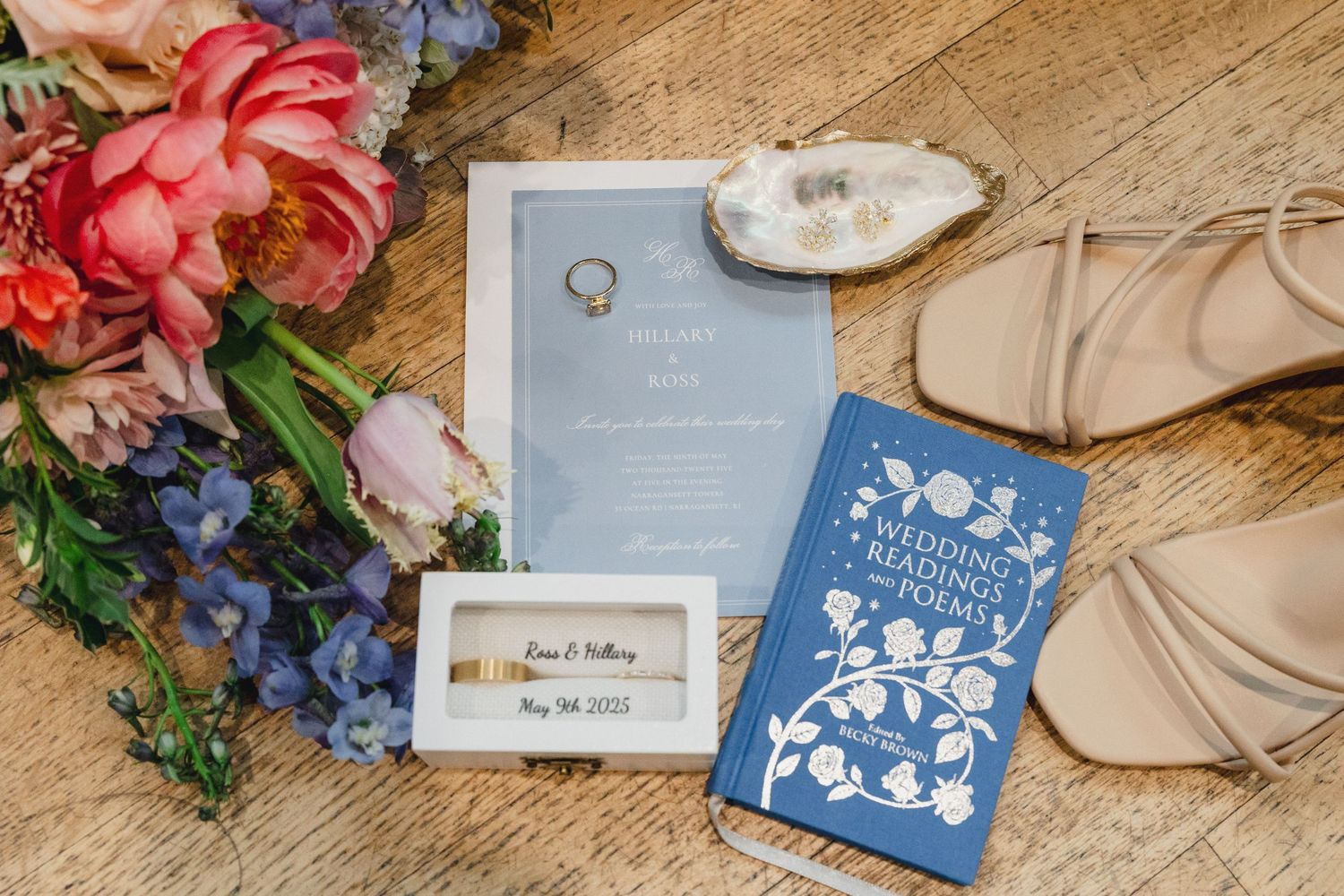 Wedding invitations and floral decorations arranged on a rustic wooden surface with navy blue and coral accents.