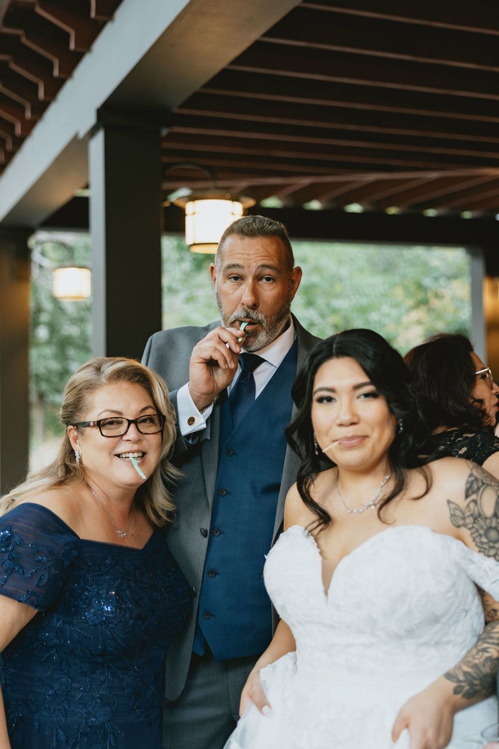 Wedding party members in navy blue and white attire laugh together under a covered outdoor venue.