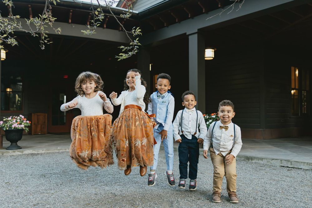 A group of people in rustic attire walking on a gravel path at an outdoor venue during a special occasion.