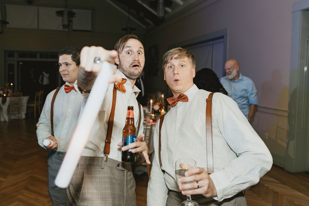 Wedding reception guests dancing and celebrating energetically in a bright indoor venue.