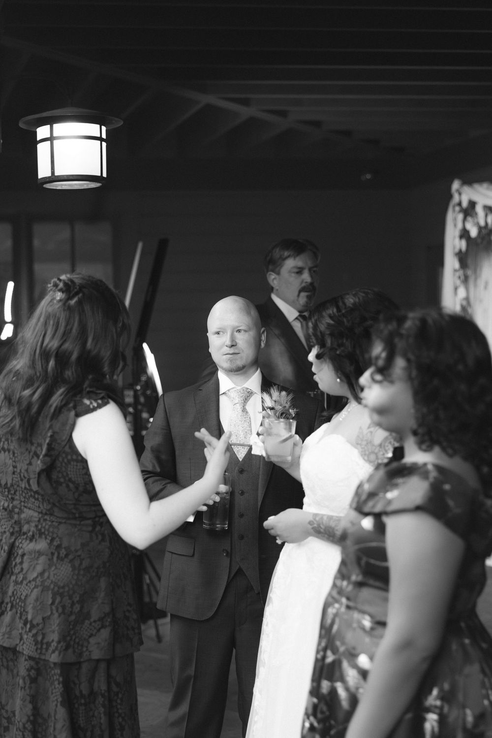 Wedding guests dancing together in a dimly lit reception venue with overhead lighting.