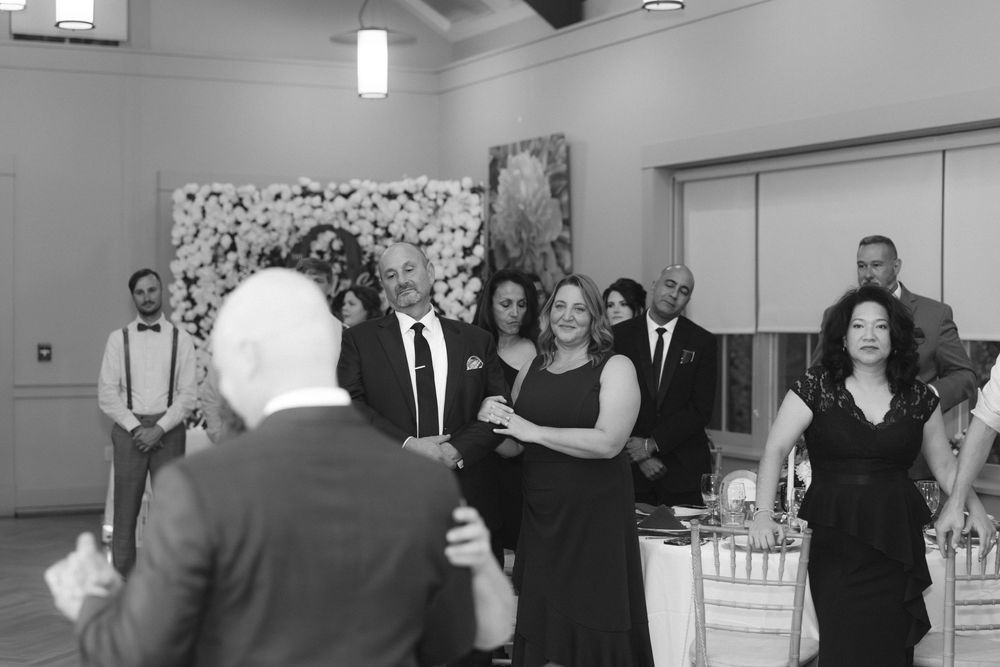 Wedding guests enjoying themselves on a monochrome dance floor at an indoor celebration.